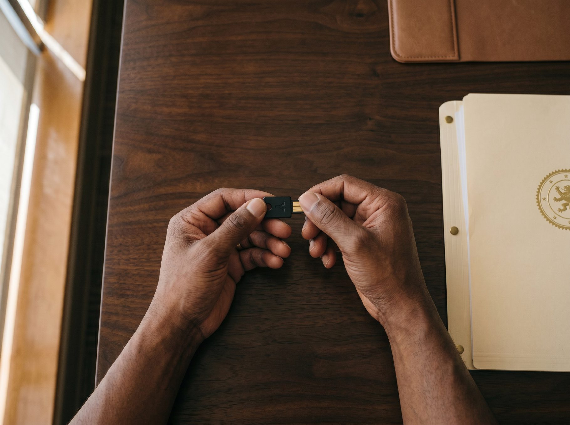 Hands holding a hardware security key at a desk